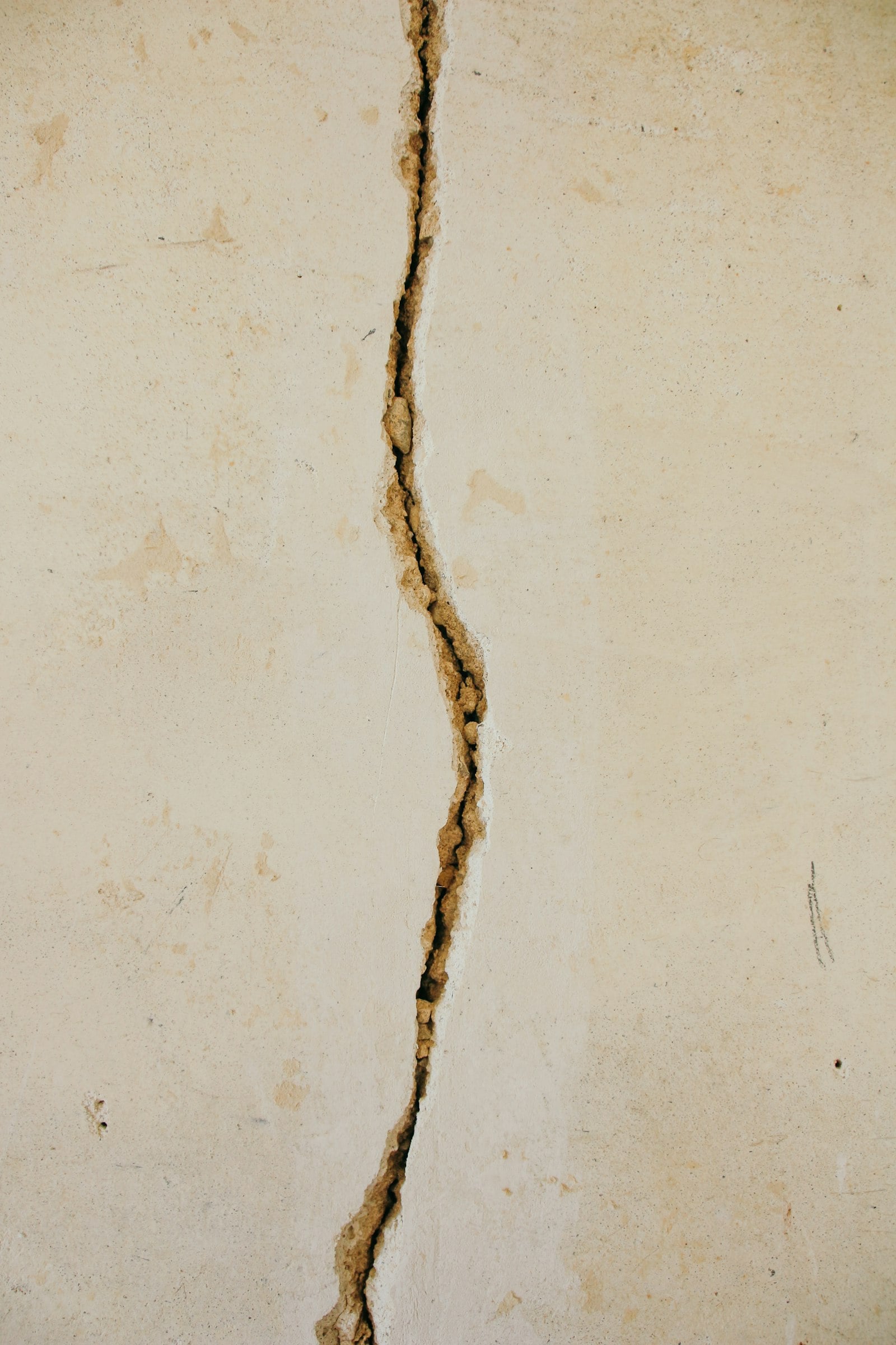 Vertical crack running through a white concrete wall