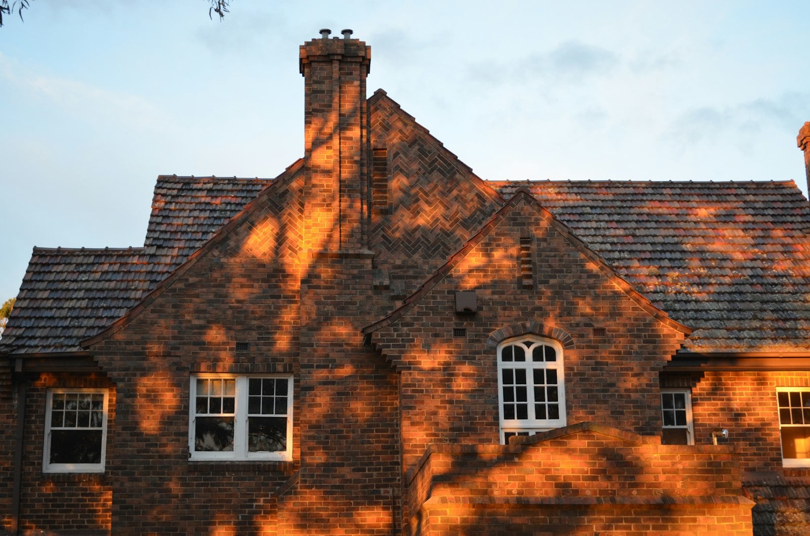 Two-story brown brick house under a blue sky